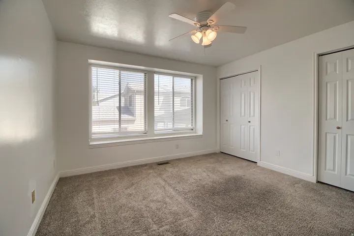 Spacious room with plush carpet flooring, white walls, and a multi-pane window with blinds