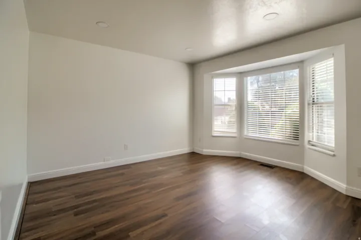 Bright, light-filled room with expansive wood-finish flooring and abundant natural light from multi-pane glass doors and transom windows