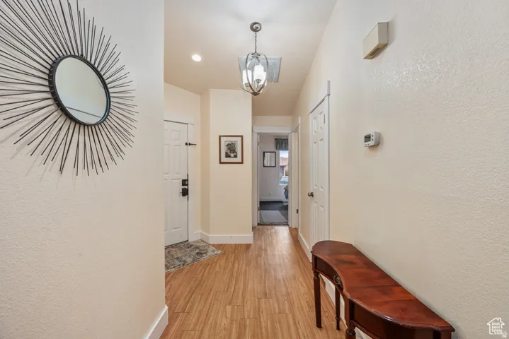 Corridor with a chandelier, and light wood finished floors