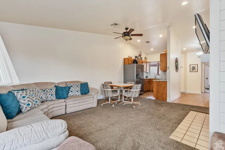 Carpeted living room with vaulted ceiling, recessed lighting, ceiling fan, and fireplace