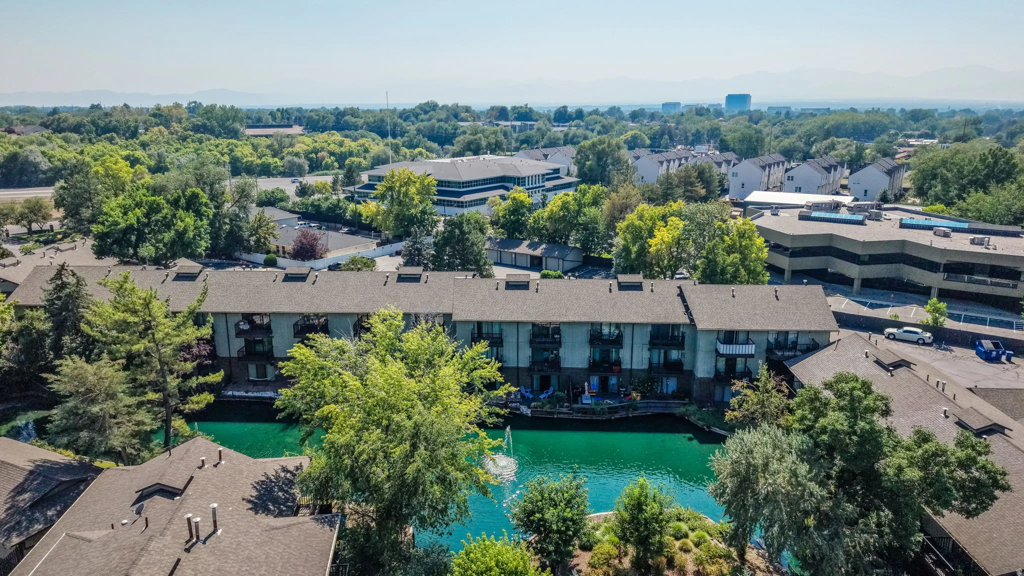Waterfront property with multiple balconies, mature trees, and a surrounding natural environment