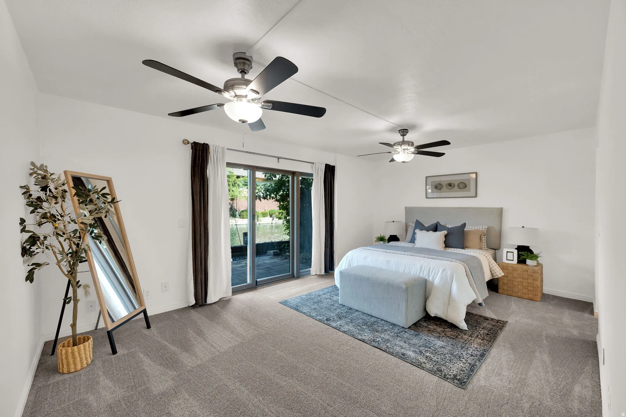 Plush gray carpeting, dual ceiling fans with integrated lighting, white walls, and sliding glass doors