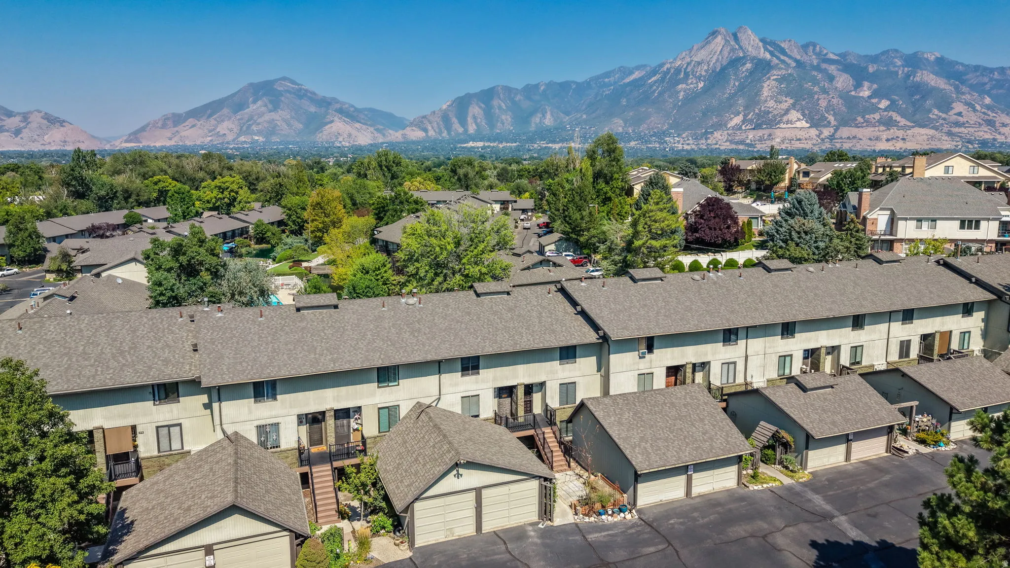 Townhome community with asphalt shingle roofs and garage structures, set against a mountain backdrop