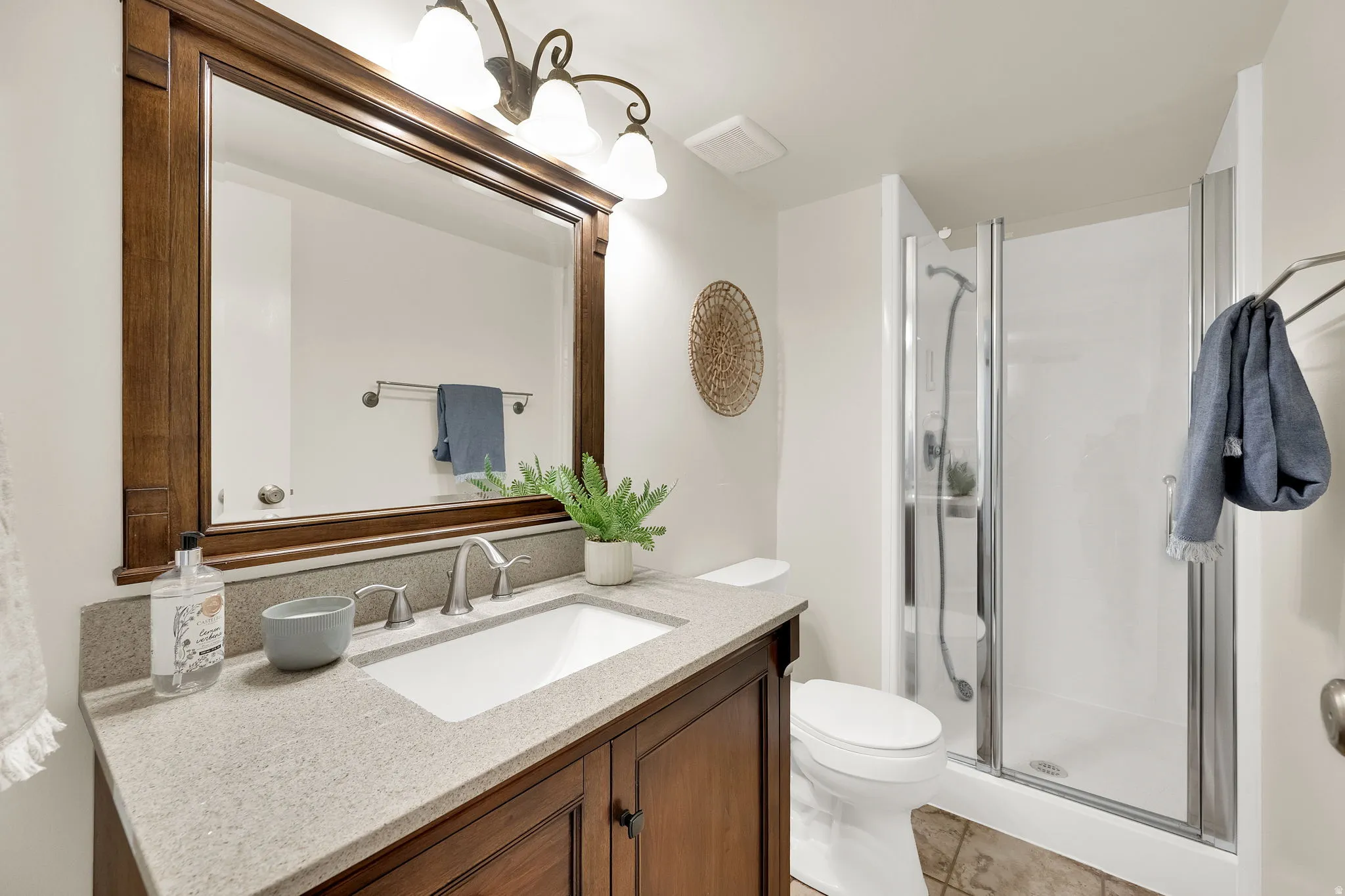 Wood-finish vanity with a light-toned countertop, undermount sink, and brushed nickel faucet