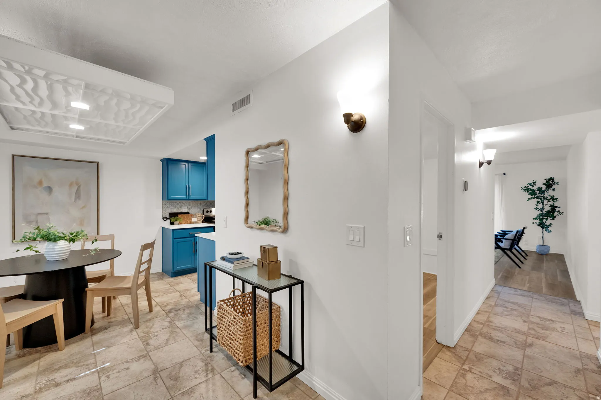 Tiled flooring throughout, wall-mounted sconce lighting, and a kitchen featuring blue cabinetry