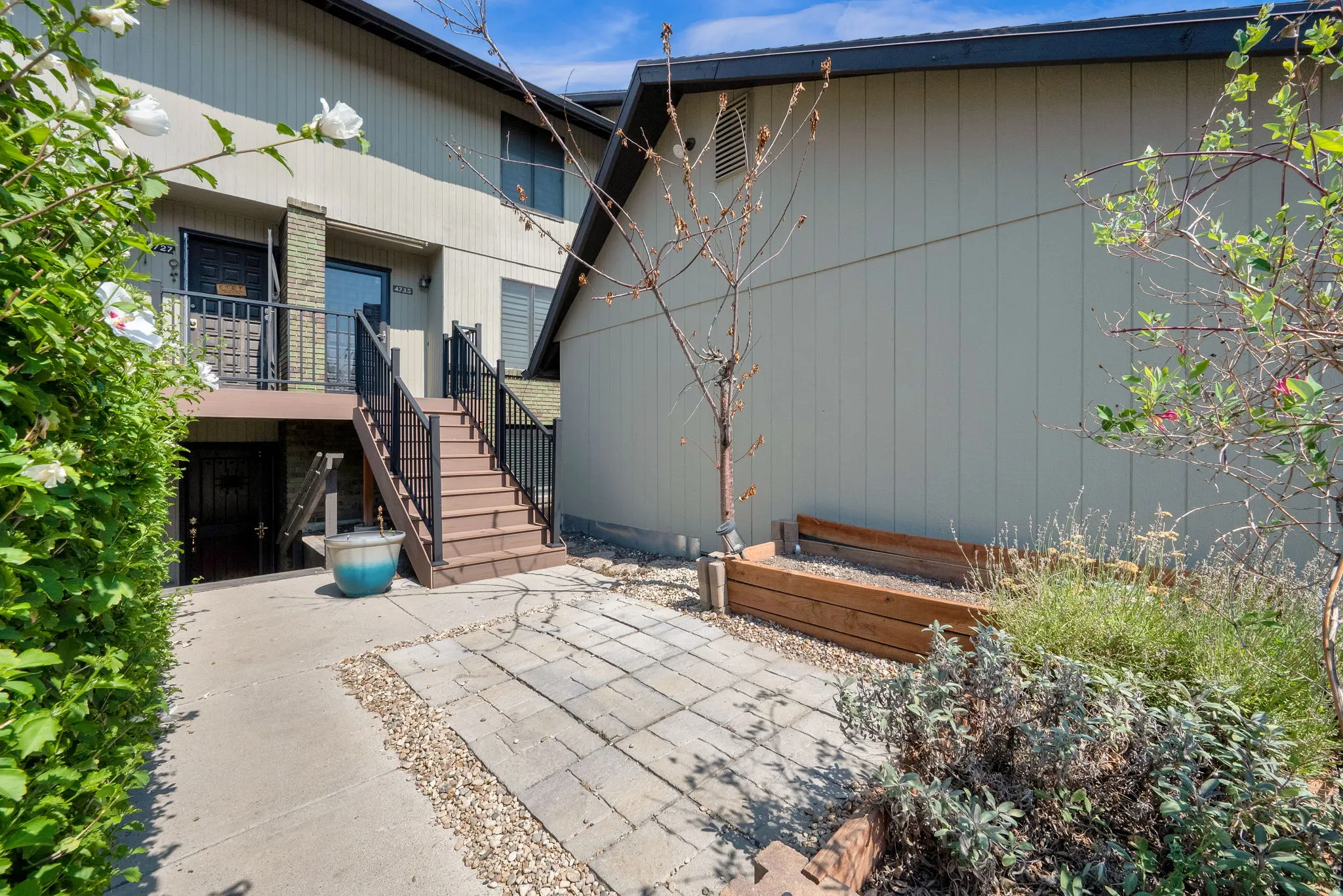 Staircase entry to main dwelling, lower-level entry, paved walkway, and raised garden beds