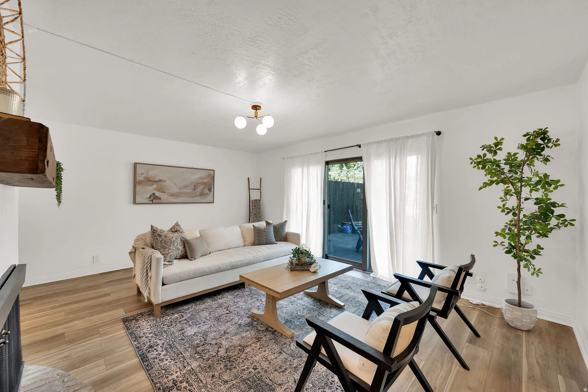 Wood-finish flooring, white walls, and a sliding glass door with sheer white curtains
