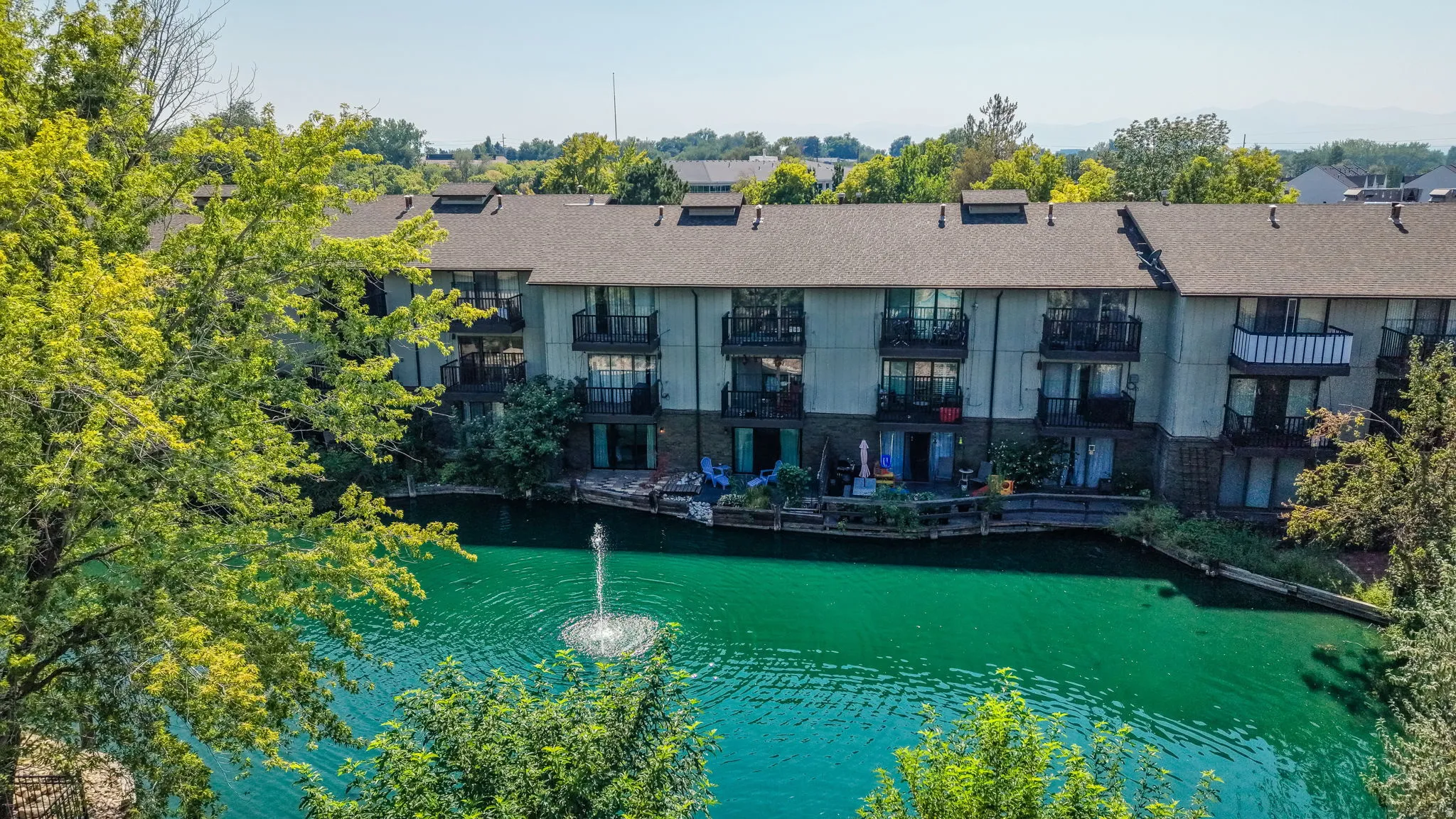 Waterfront setting with a visible water feature, private balconies, and mature landscaping