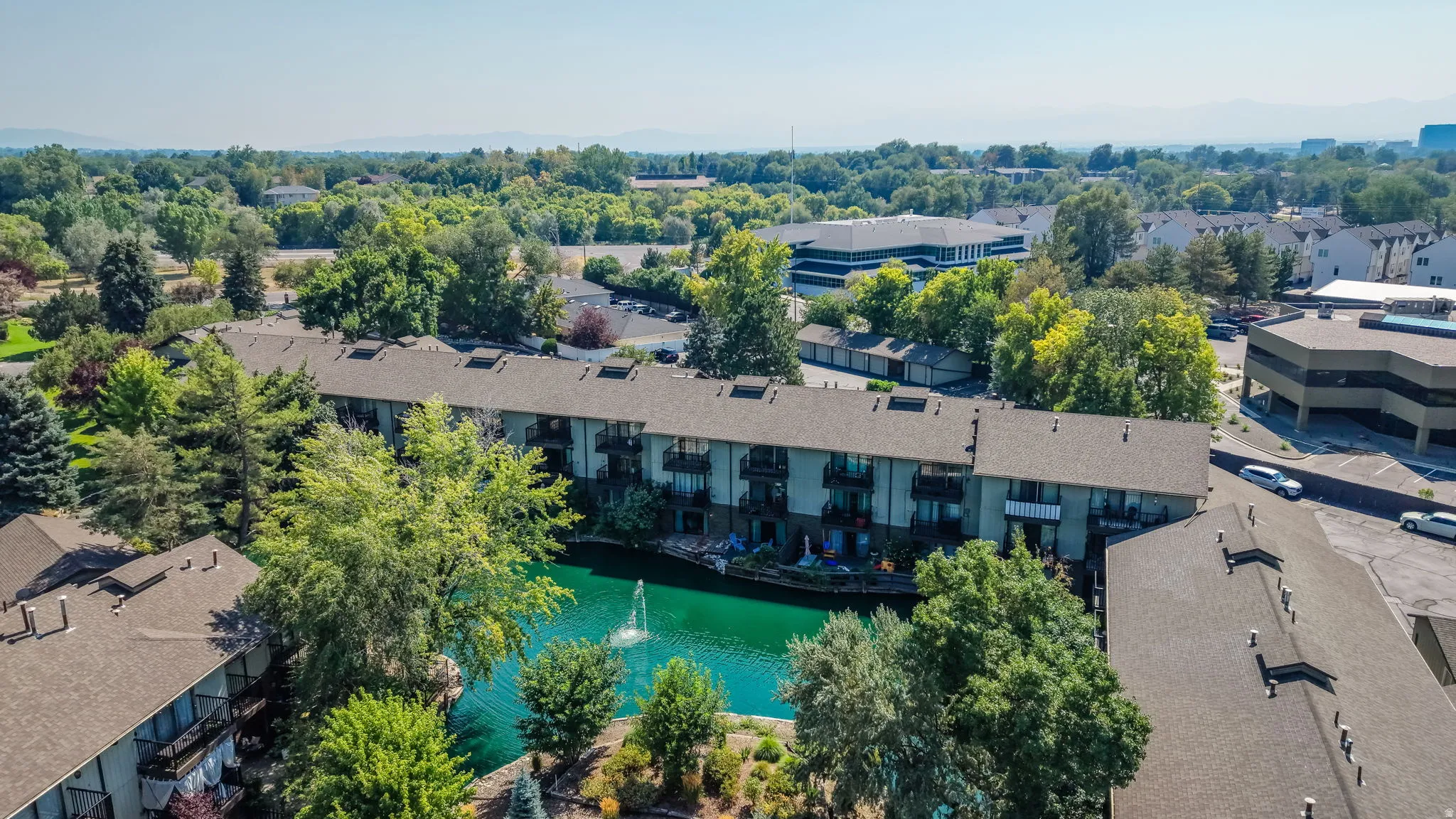 Multi-story residential buildings featuring balconies, surrounded by mature trees and landscaping