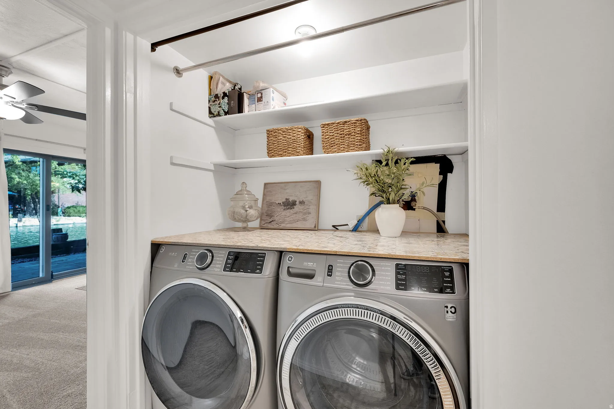 Recessed laundry area featuring a light-toned countertop, built-in shelving, and a hanging rod