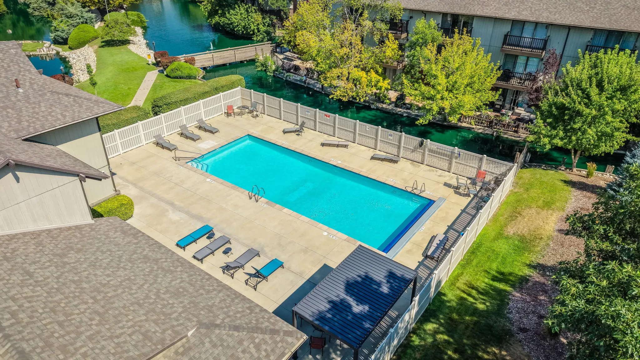 Rectangular swimming pool with a surrounding concrete deck, enclosed by a white picket fence