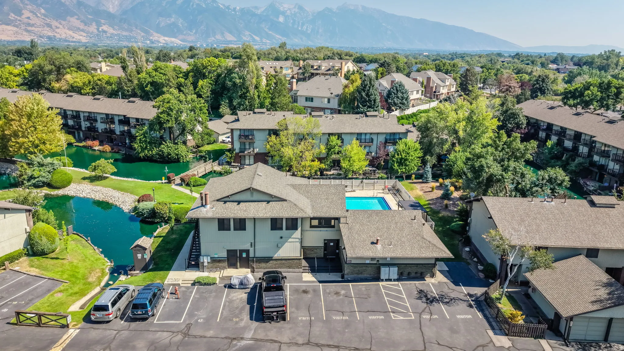 Community with mature landscaping, a swimming pool, and a pond feature