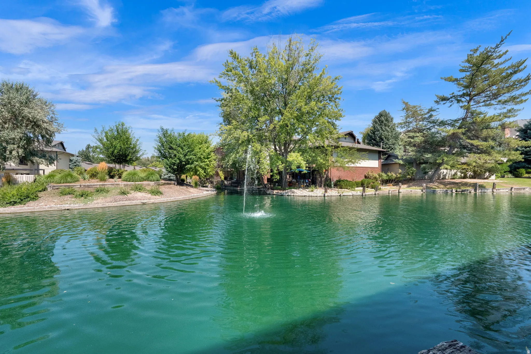 Water feature with fountain, surrounded by mature trees and landscaping
