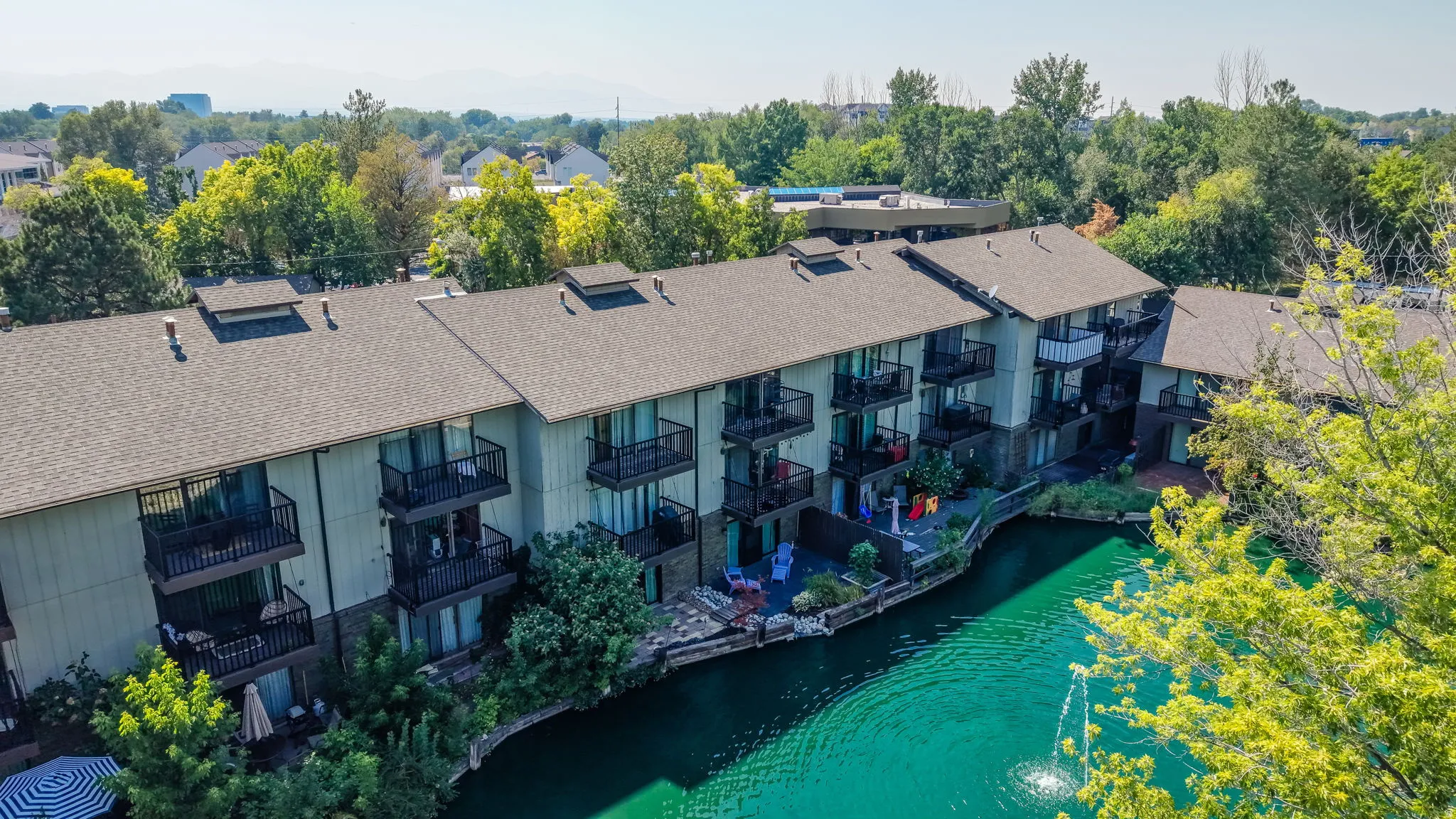 Multi-story building featuring balconies, direct water access, and surrounding mature trees