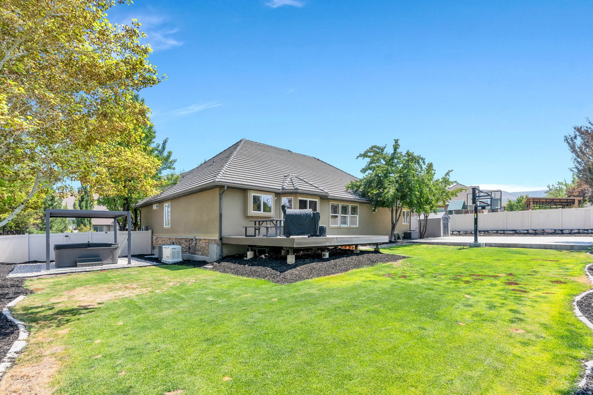 Expansive rear yard featuring a stucco exterior with stone accents and a multi-level deck