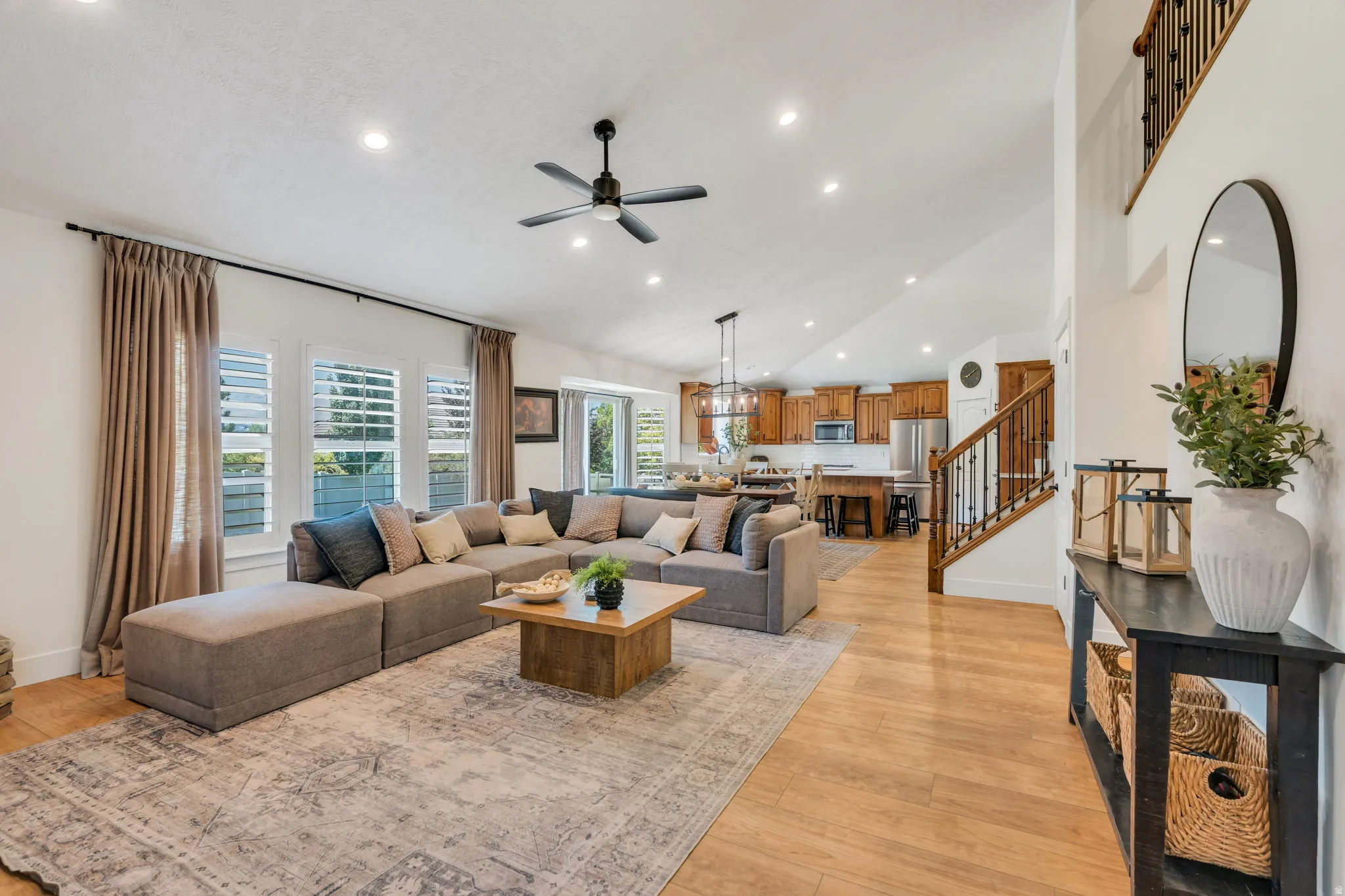 Spacious living area featuring vaulted ceilings with recessed lighting and a ceiling fan