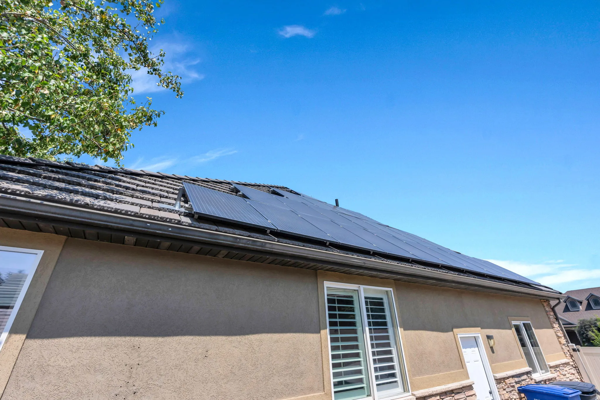 Residential roof featuring solar panels, dark tile roofing, and a gutter system