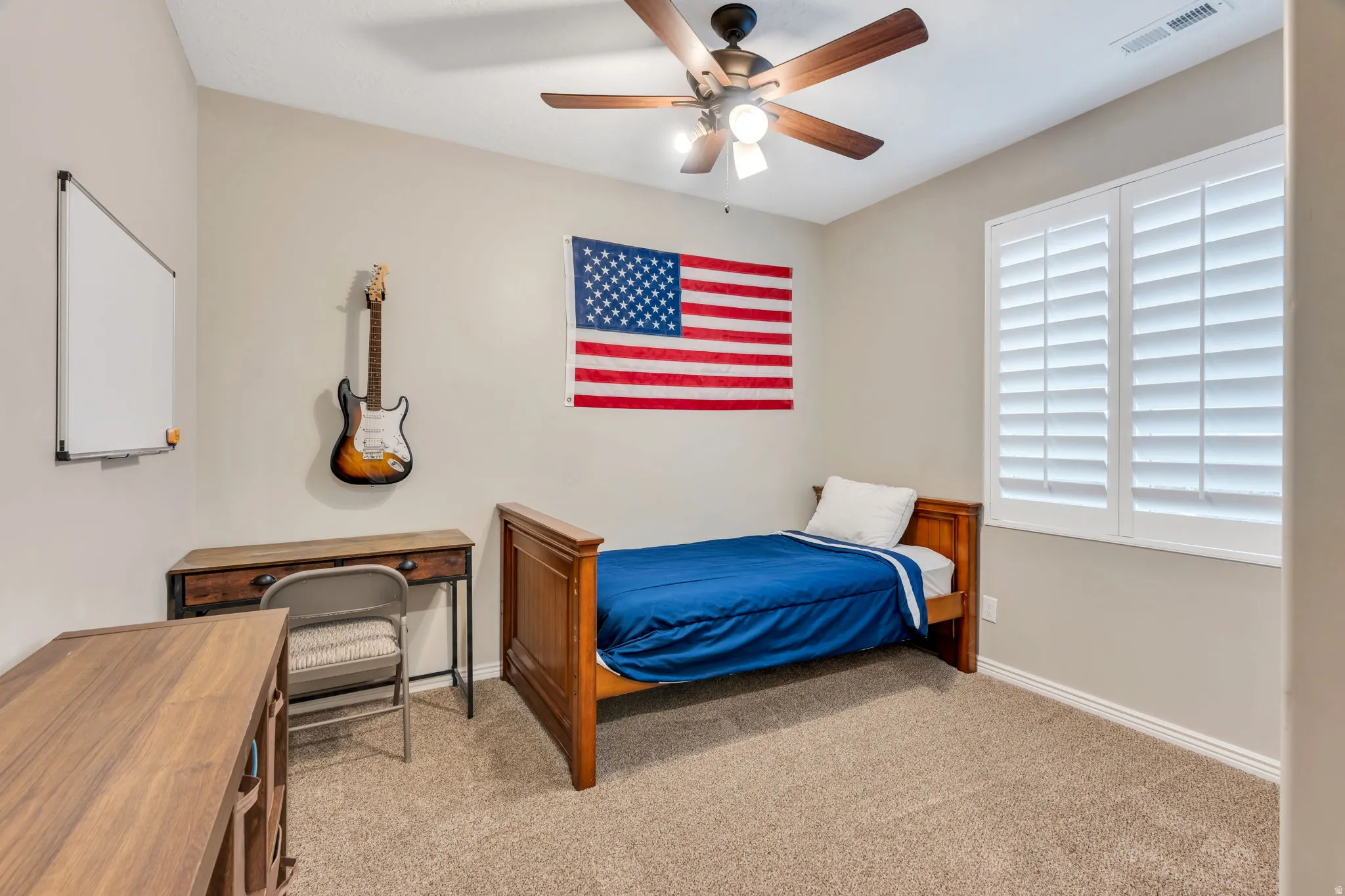 Carpeted room featuring a ceiling fan, white plantation shutters, and light neutral walls