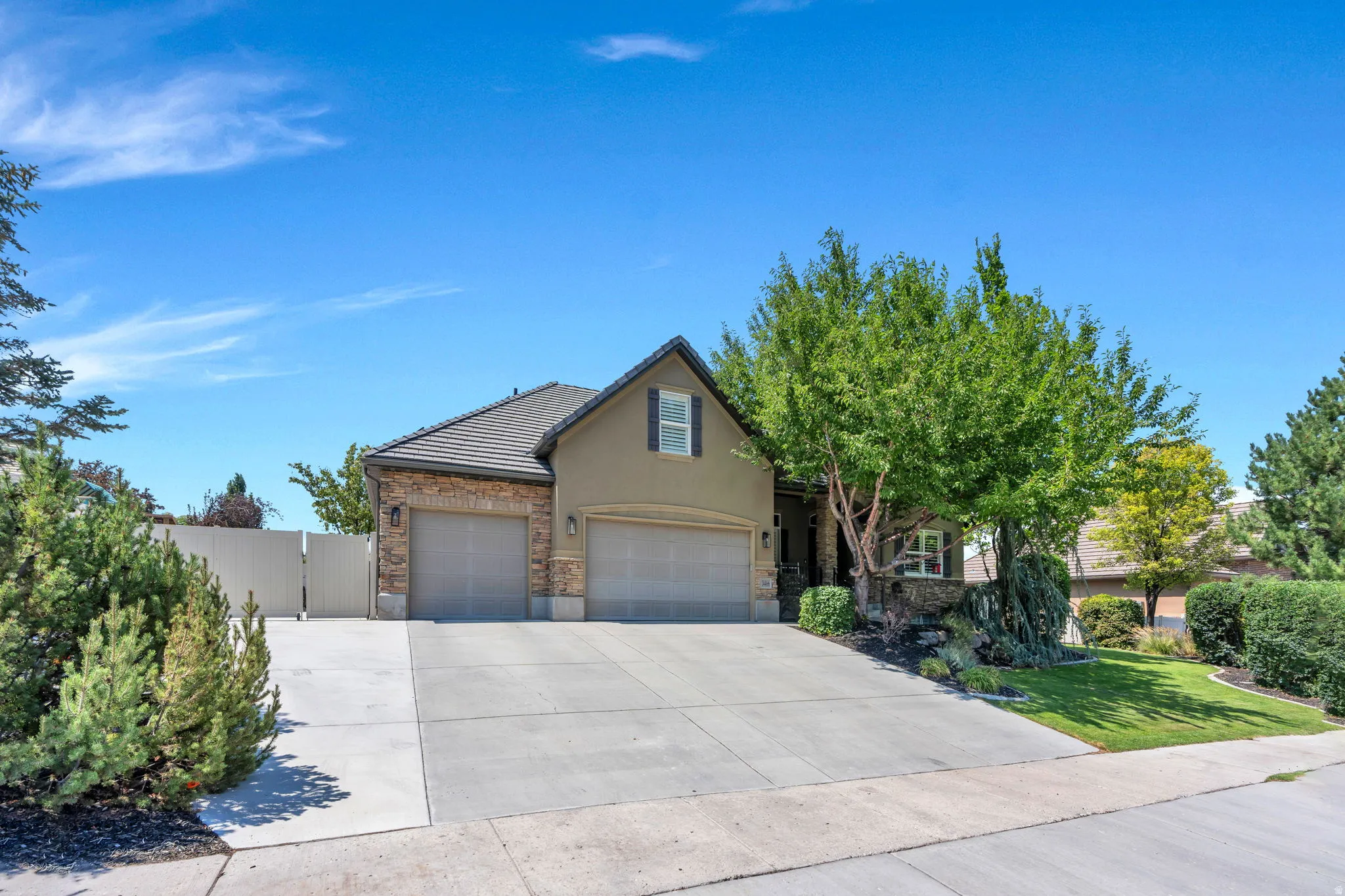 Two-story residence featuring a stone and stucco exterior, a two-car garage, and a concrete driveway