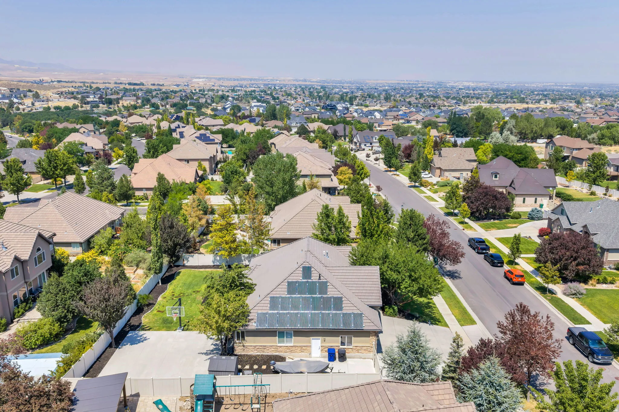 Aerial view showcasing this residential property nestled in an established neighborhood with mature landscaping, manicured lawns, and tree-lined streets