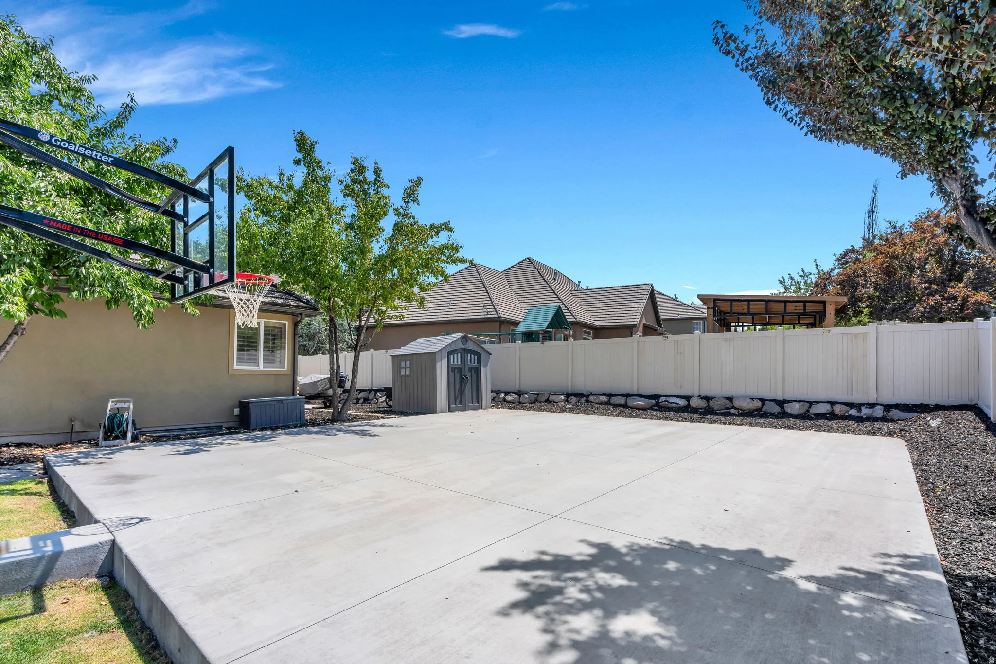 Expansive concrete pad, ideal for recreation, bordered by a white privacy fence
