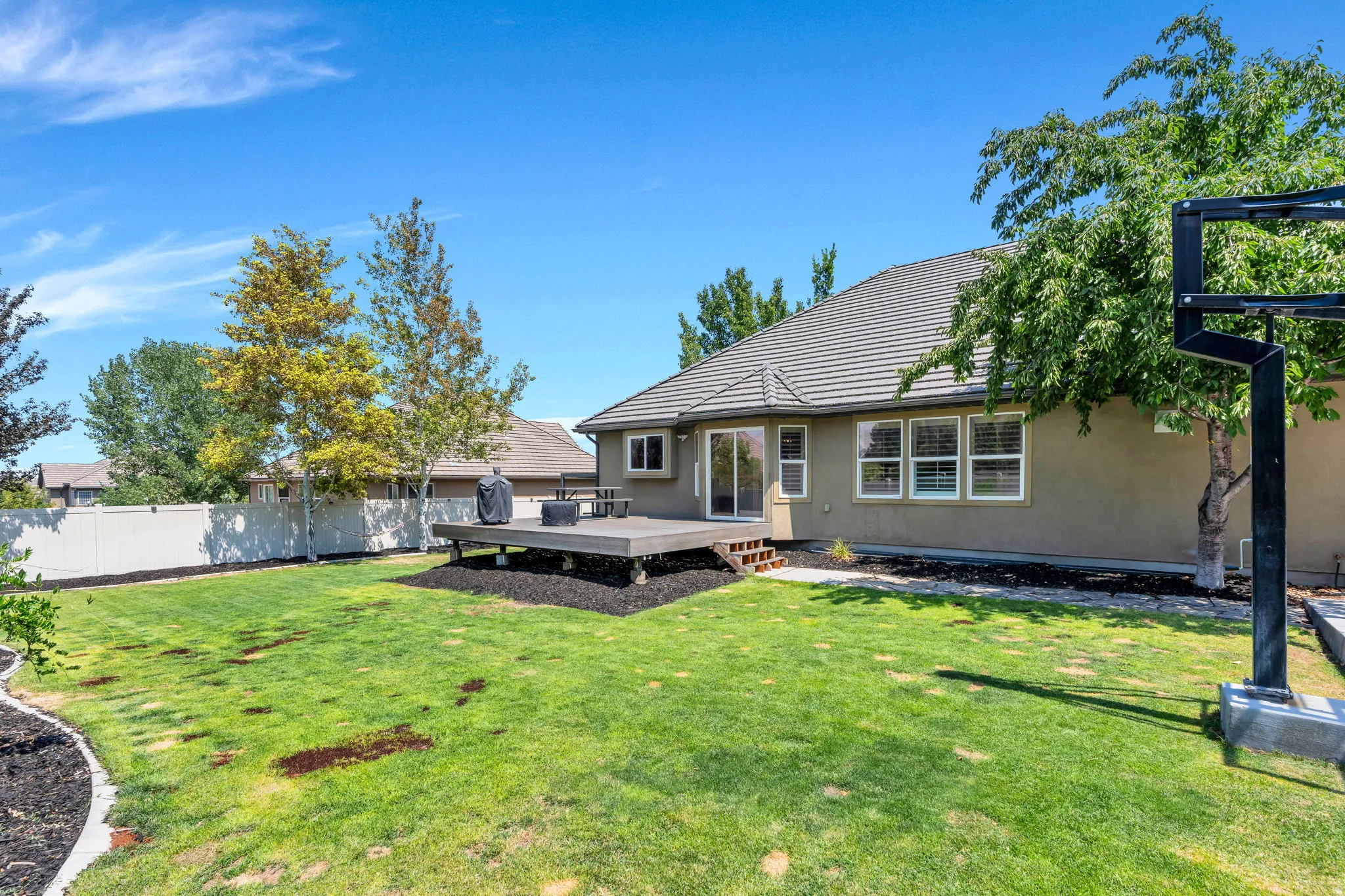Expansive backyard featuring a manicured lawn, a large elevated deck, and a privacy fence