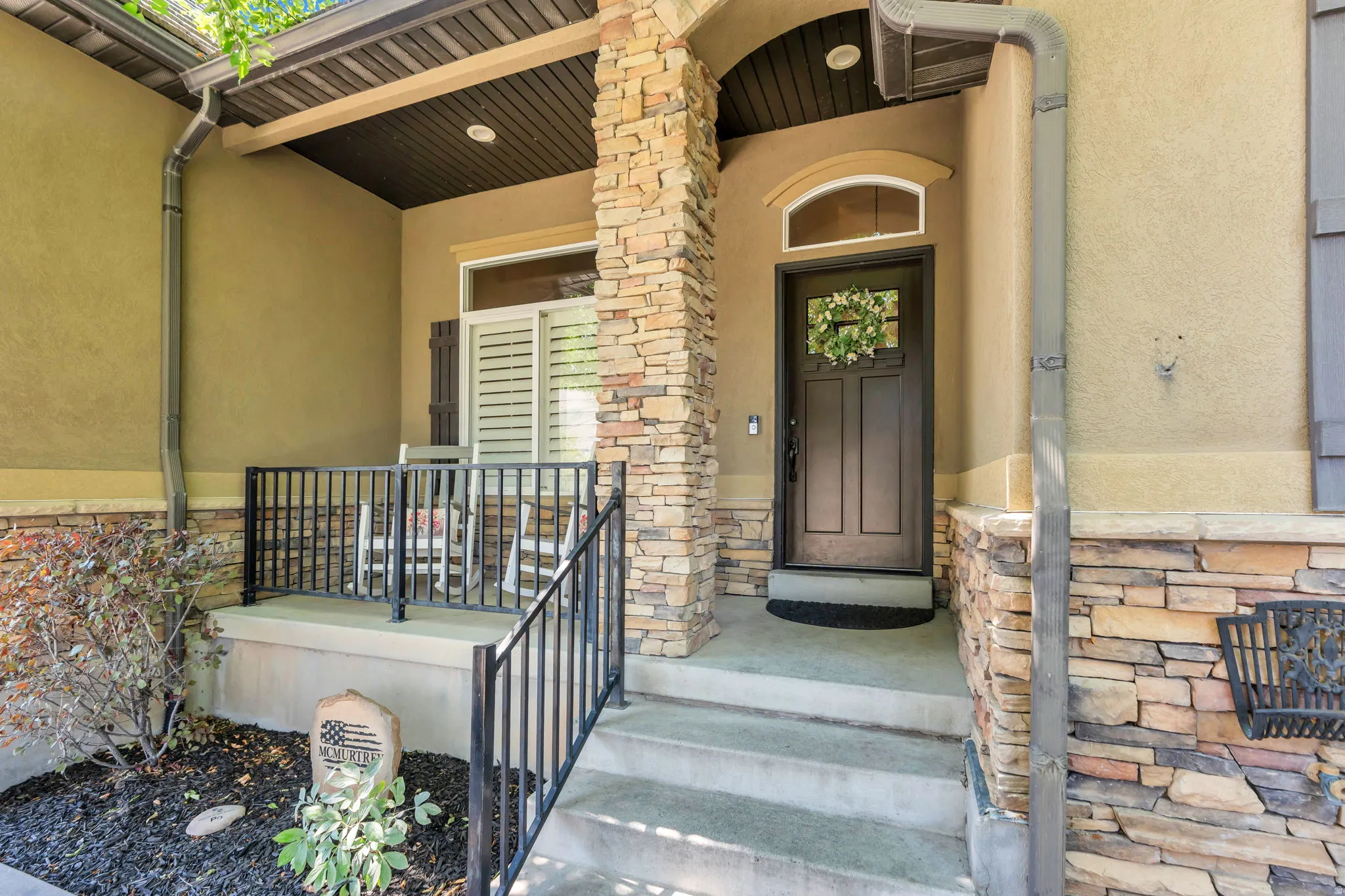 Stucco exterior featuring stacked stone accents and a covered porch