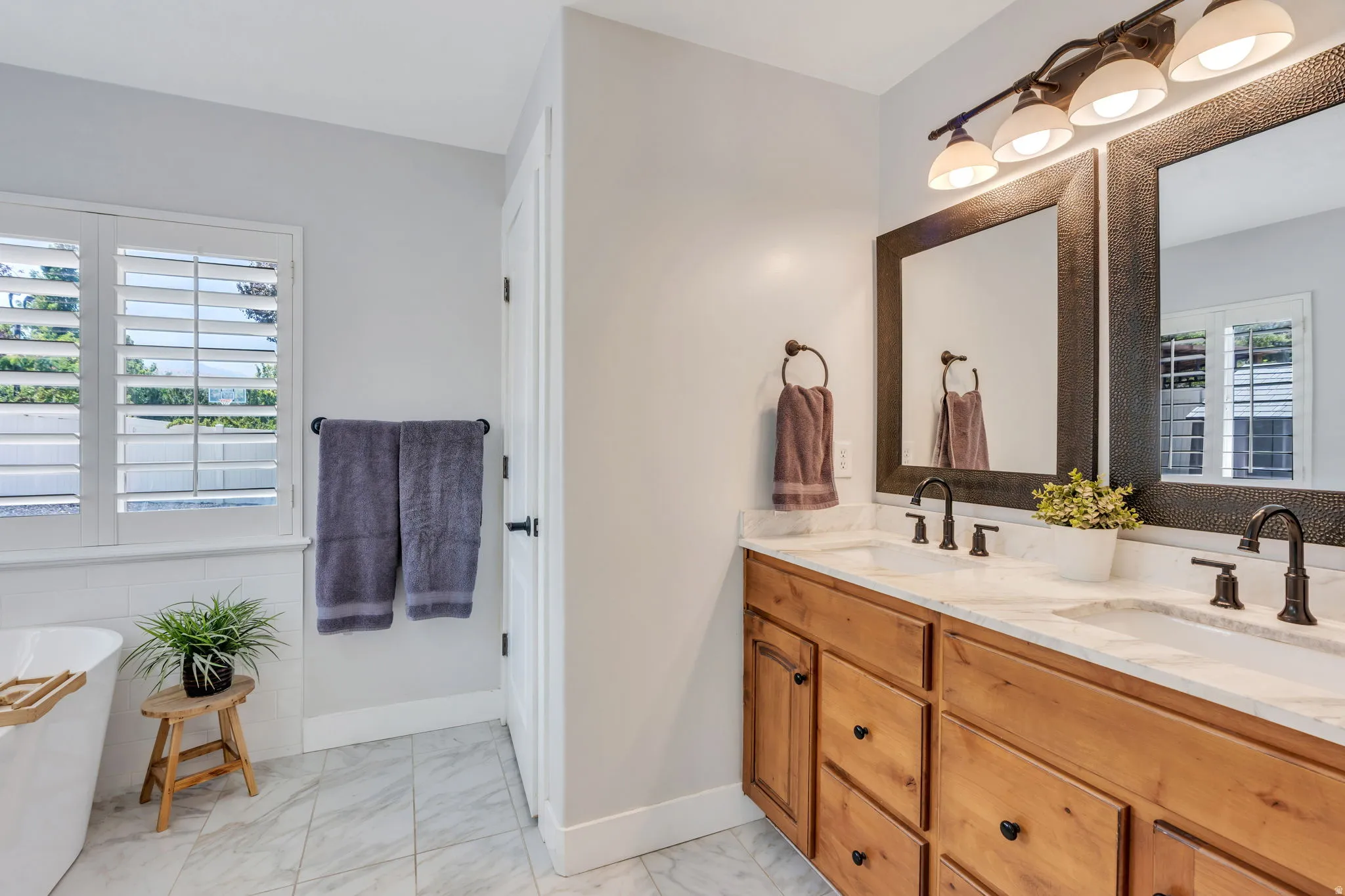 Dual vanity with wood cabinetry, light-toned countertops, and dark bronze fixtures
