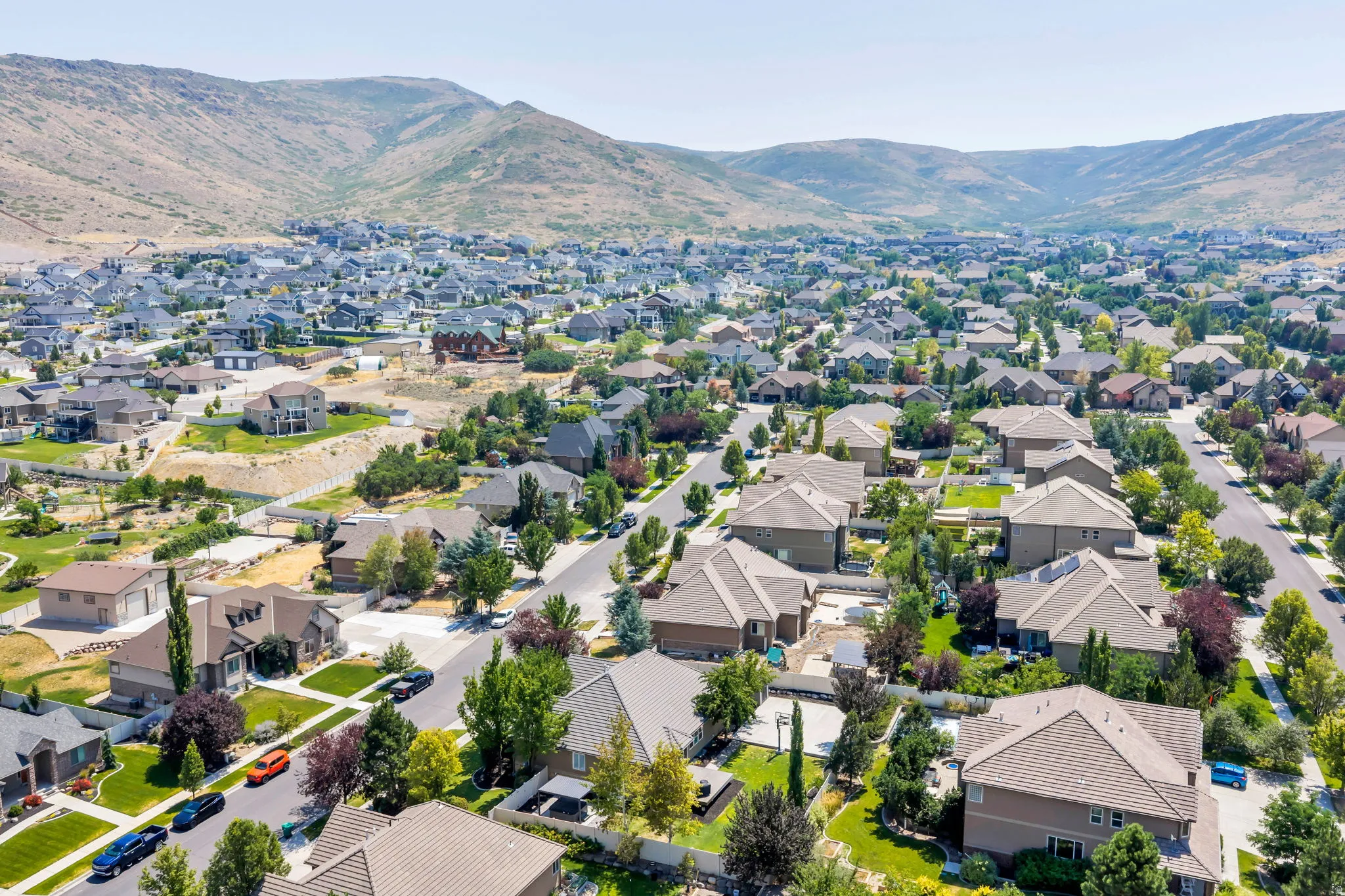 Residential neighborhood featuring mature landscaping and paved streets, framed by distant mountains
