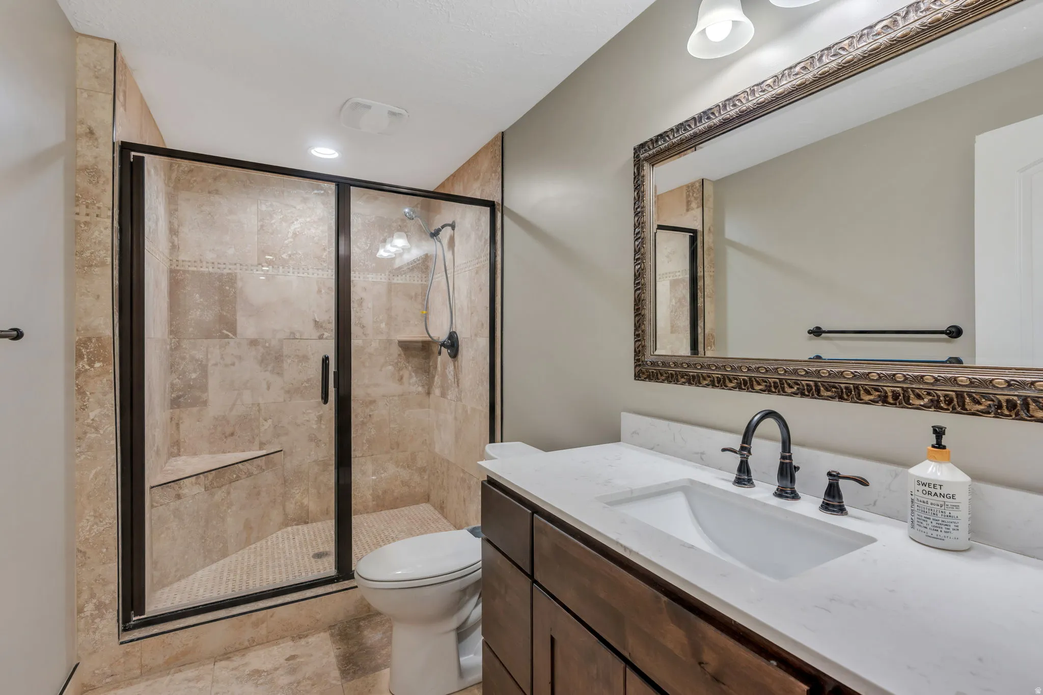 Shower with full tile surround, built-in bench, and black-framed glass enclosure