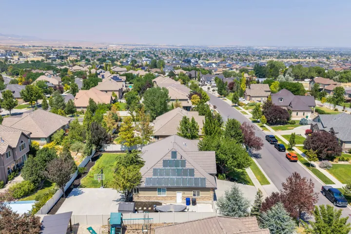 Aerial view showcasing this residential property nestled in an established neighborhood with mature landscaping, manicured lawns, and tree-lined streets