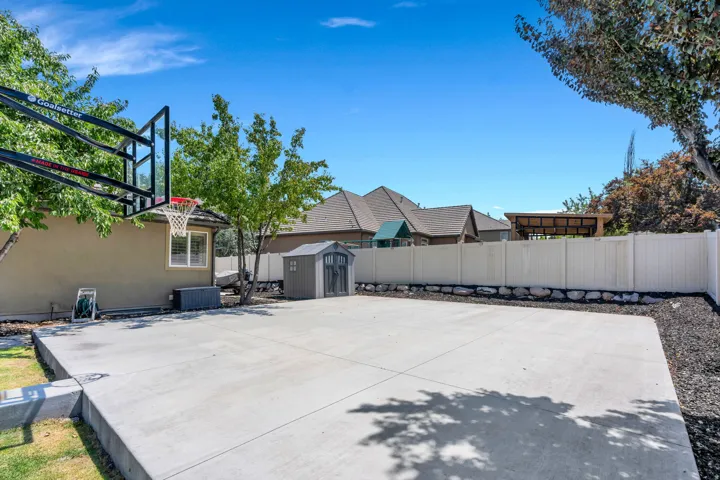 Expansive concrete pad, ideal for recreation, bordered by a white privacy fence