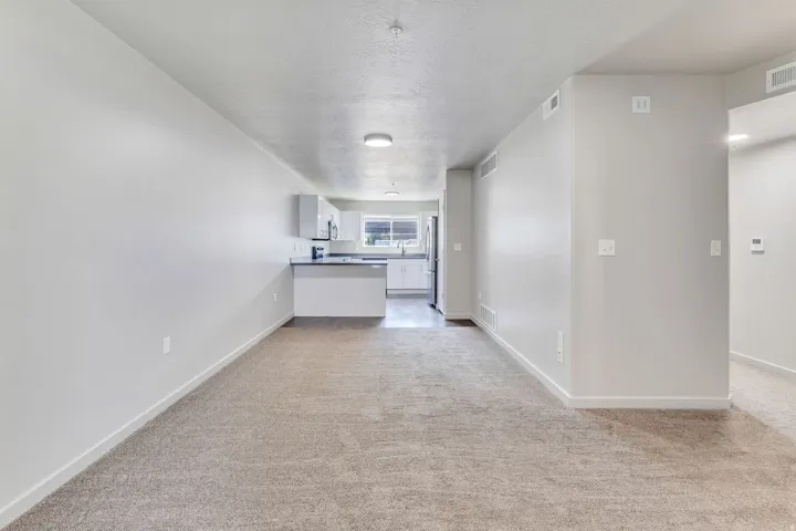 Open-concept living area with neutral wall finishes, recessed ceiling lighting, and neutral-tone carpeting