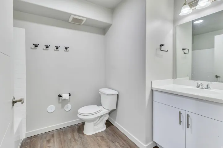 Modern bathroom featuring dual vanity with white cabinetry and brushed nickel hardware, quartz countertop, and chrome faucet