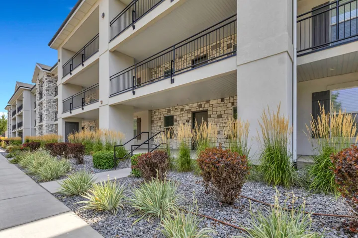 Multi-story building with stone and stucco exterior, featuring individual balconies with black railings