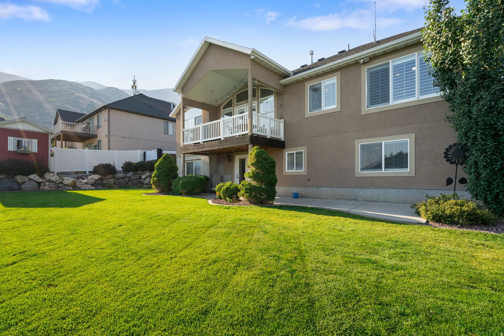 Expansive manicured lawn with mature landscaping and evergreen plantings, backed by mountain vistas