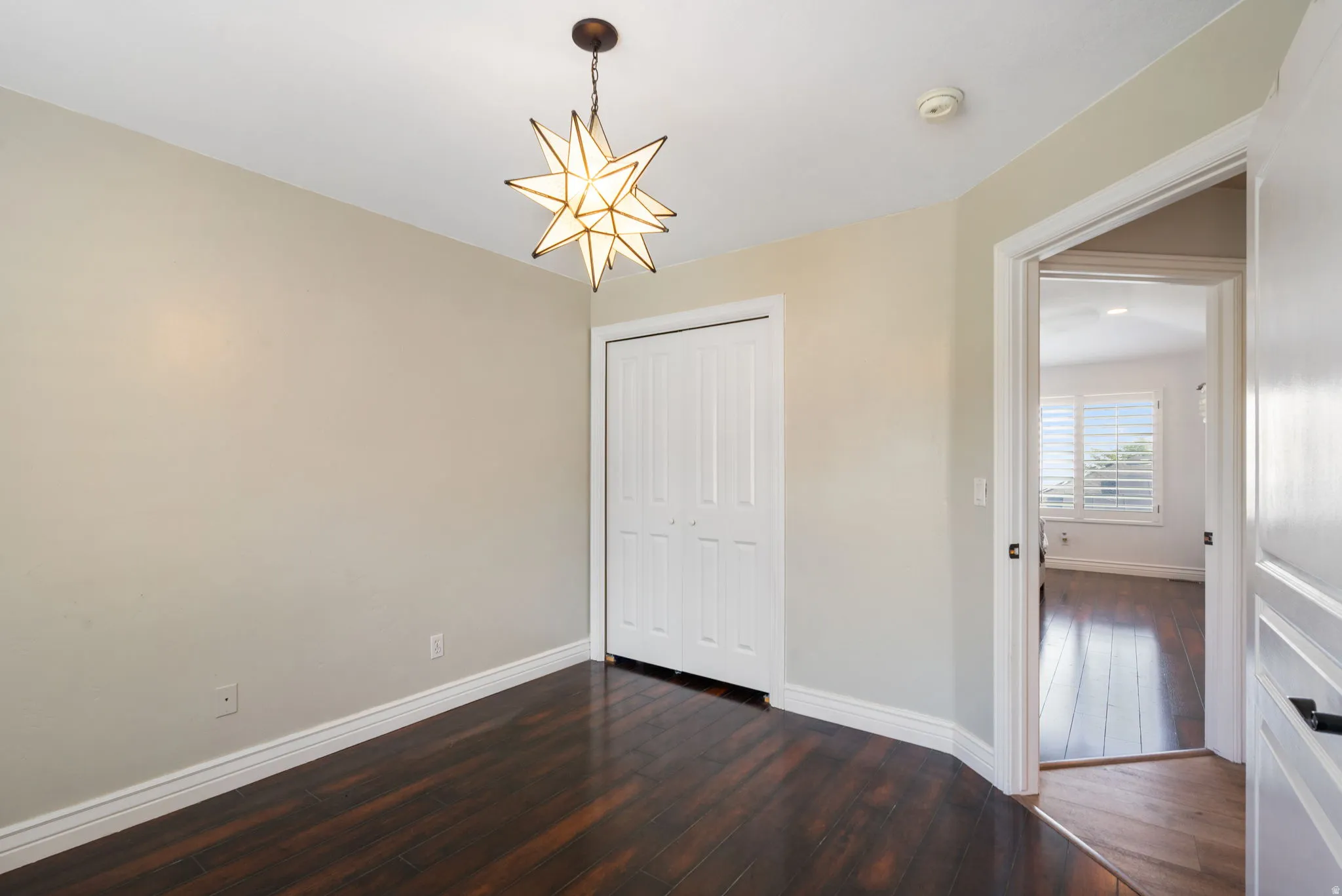 Dark wood-finish flooring, white bifold closet doors, and a star-shaped ceiling fixture
