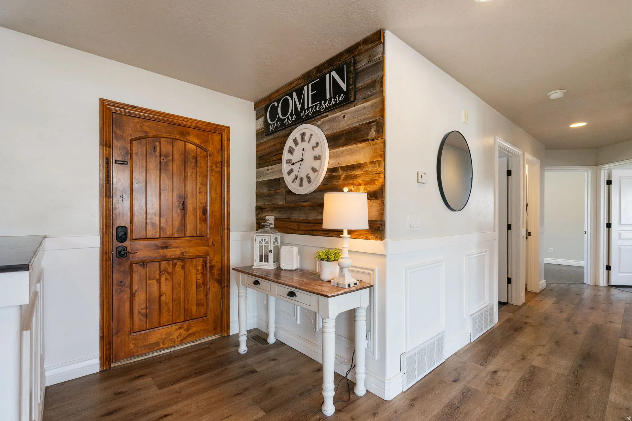 Wood-finish flooring, white wainscoting, and a wood plank accent wall