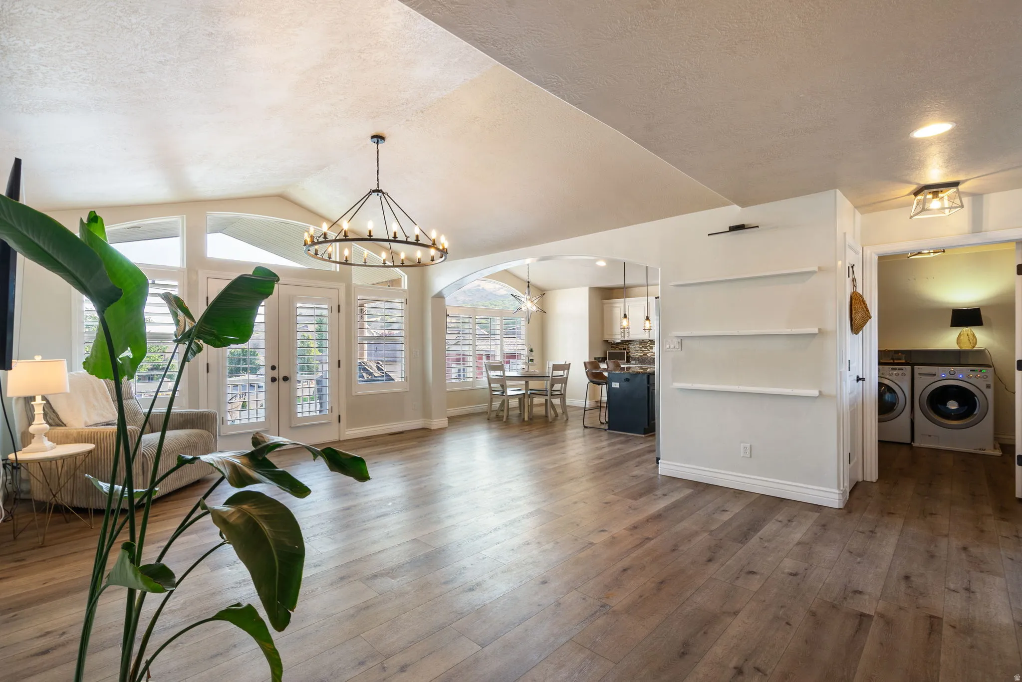 Open-concept living space featuring wood-finish flooring throughout, vaulted ceilings with skylights, and a chandelier pendant fixture