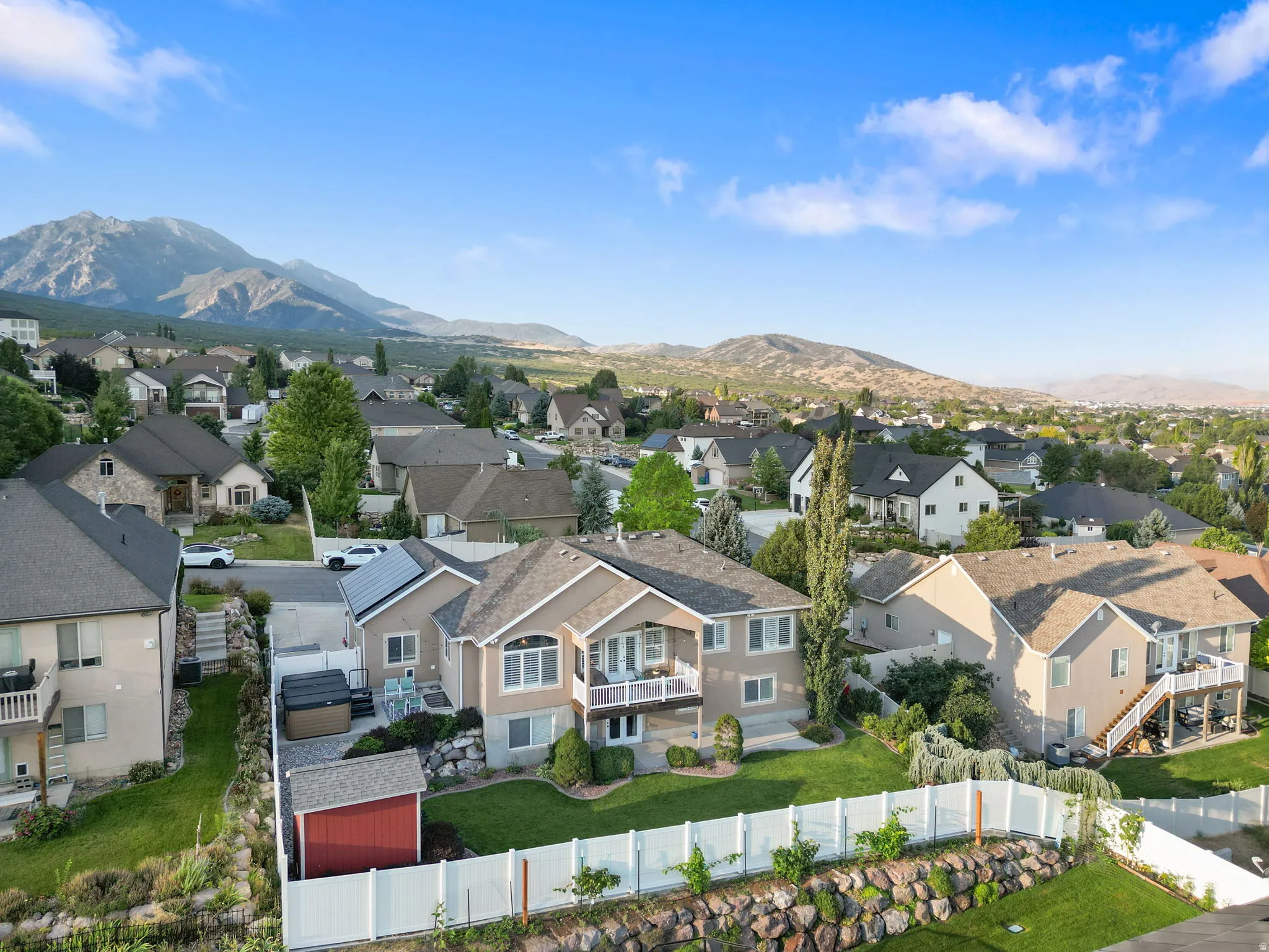 Stunning two-story residence showcasing a manicured lawn with mature landscaping, white perimeter fencing, and a detached garage