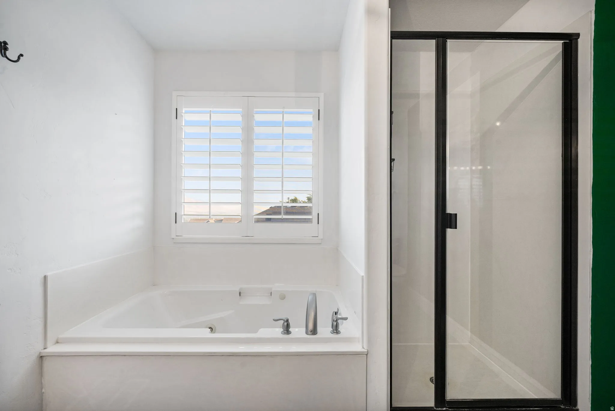Soaking tub with white plantation shutters and brushed nickel fixtures