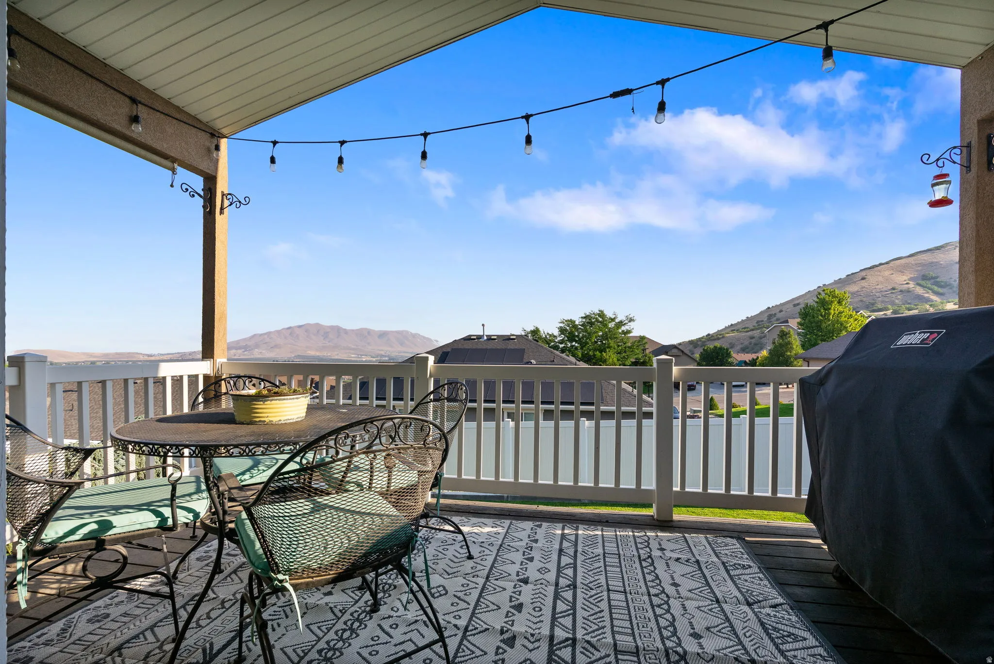 Covered balcony with wood-finish flooring, white railing, and mountain scenery