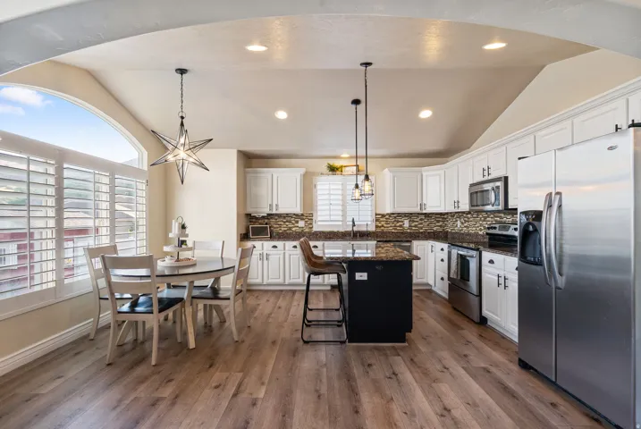 Kitchen featuring wood-finish flooring, white cabinetry, dark countertops, and stainless steel appliances