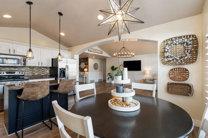 Vaulted ceilings, kitchen island with seating, stainless steel appliances, wood-finish flooring, and an arched doorway