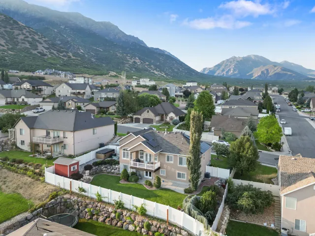 Expansive backyard featuring a manicured lawn, white privacy fence, and rock retaining wall