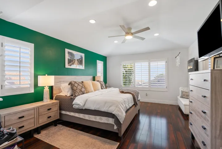 Dark wood-finish flooring with white baseboards, recessed lighting, and a ceiling fan