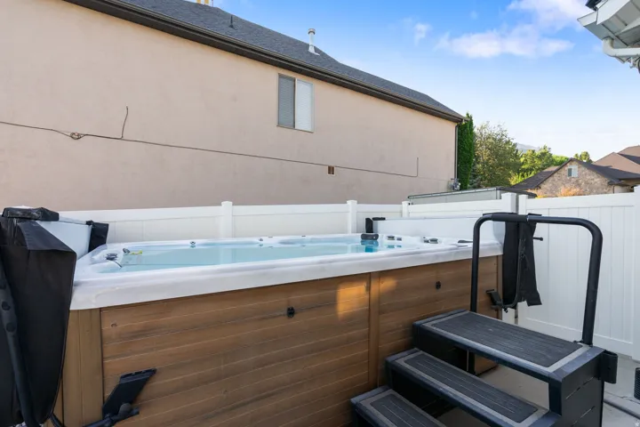 Luxurious hot tub with integrated jets and wood-finish exterior surround, featuring a multi-step entry system and white acrylic interior