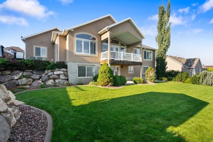 Expansive rear yard featuring a manicured lawn, established landscaping, and a multi-level deck with white railings