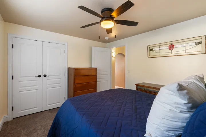 Carpeted room with a ceiling fan, white paneled doors, and an arched doorway