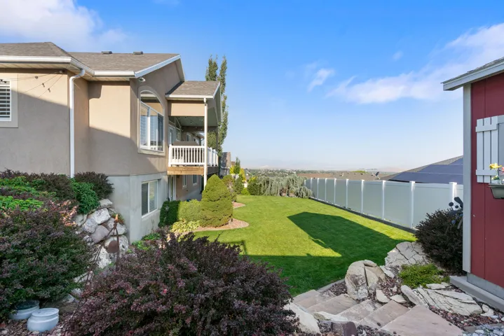 Expansive backyard featuring a manicured lawn, established landscaping, and a privacy fence
